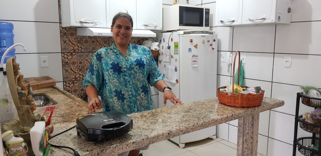 A imagem mostra Marcelle a frente do balcão da sua cozinha americana: ela cuida sozinha da sua casa e da sua própria vida. 